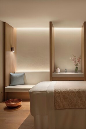 A modern hotel room with a bed, a seating area, a small table with a vase, and a bowl on the floor. - The Laurus, a Luxury Collection Resort, Singapore (Singapore)