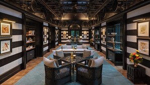 Une pièce spacieuse avec un coin salon central, des étagères et des œuvres d’art accrochées aux murs.