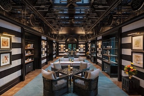 A spacious room with a central seating area, bookshelves, and artwork on the walls.