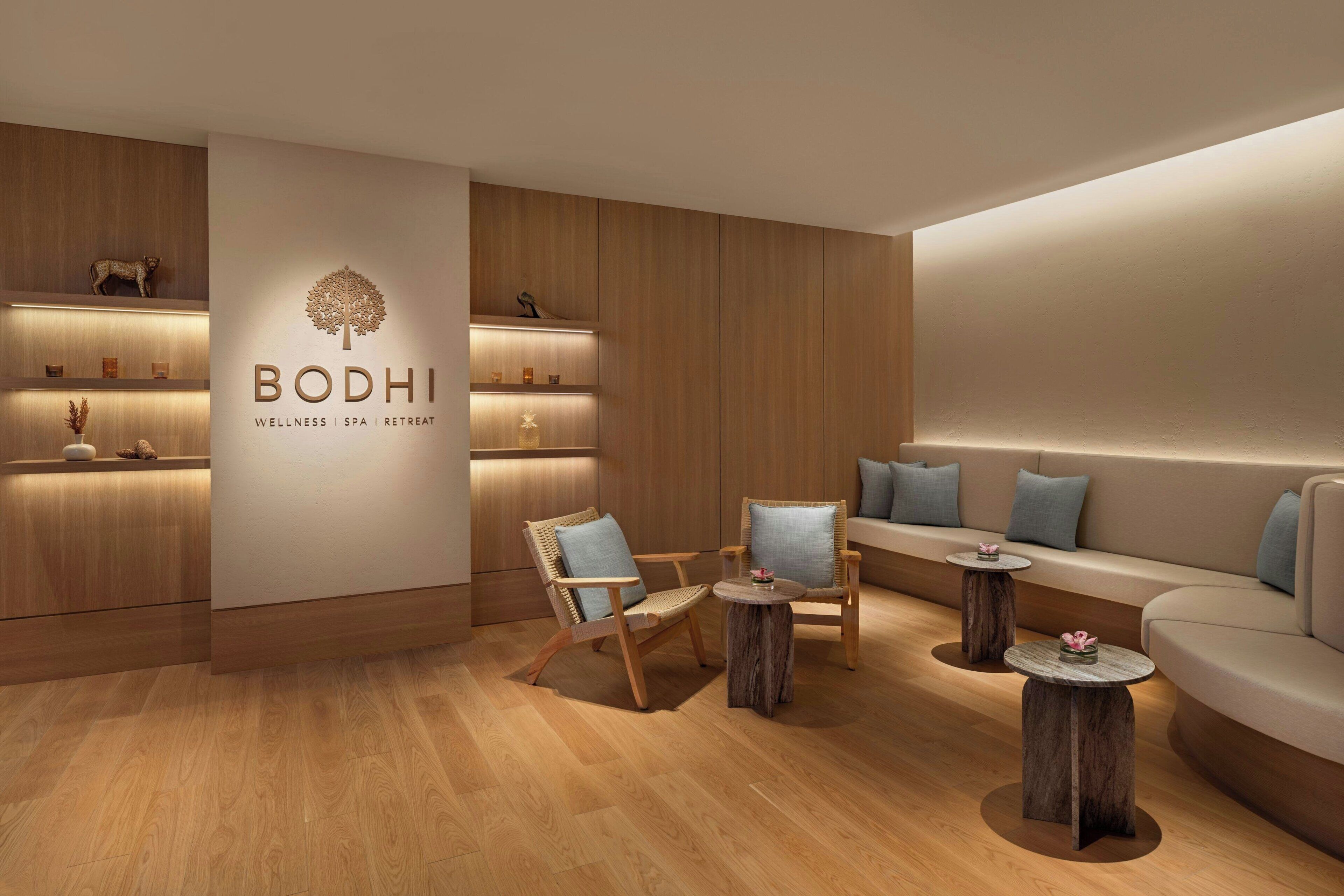 A modern wellness spa retreat with wooden flooring, a reception desk, seating areas, and a wall-mounted display.