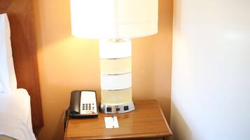 Un comodino con una lampada, un telefono e un quaderno.