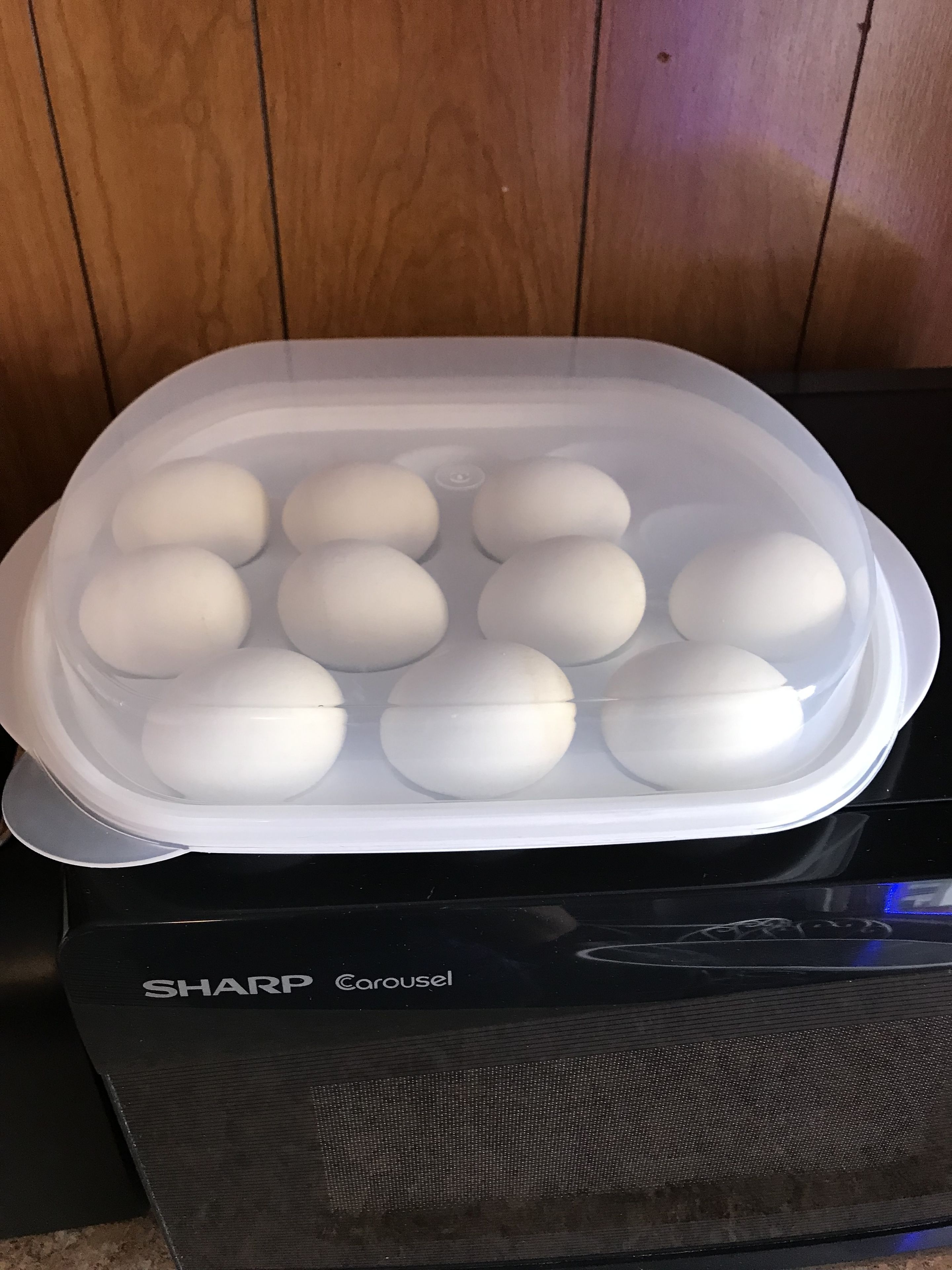 A plastic container with eggs on a black appliance.
