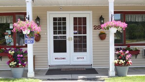 A building with a double door labeled "WELCOME" and "OFFICE," a "PARKING ONLY" sign, and flower baskets on either side of the entrance. - Cozy Corner Motel (Williamstown)