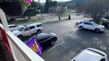 Un estacionamiento con varios coches, un edificio blanco y una colina al fondo.