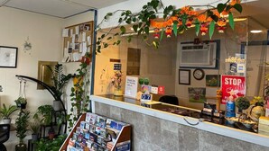 A reception area with a bulletin board, a 'no smoking' sign, a clock, and a 'STOP' sign. - Cozy Corner Motel (Williamstown)