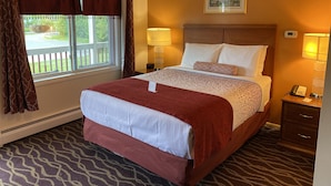 A hotel room with a large bed, two bedside lamps, a nightstand, a framed picture on the wall, and a window with curtains. - Cozy Corner Motel (Williamstown)