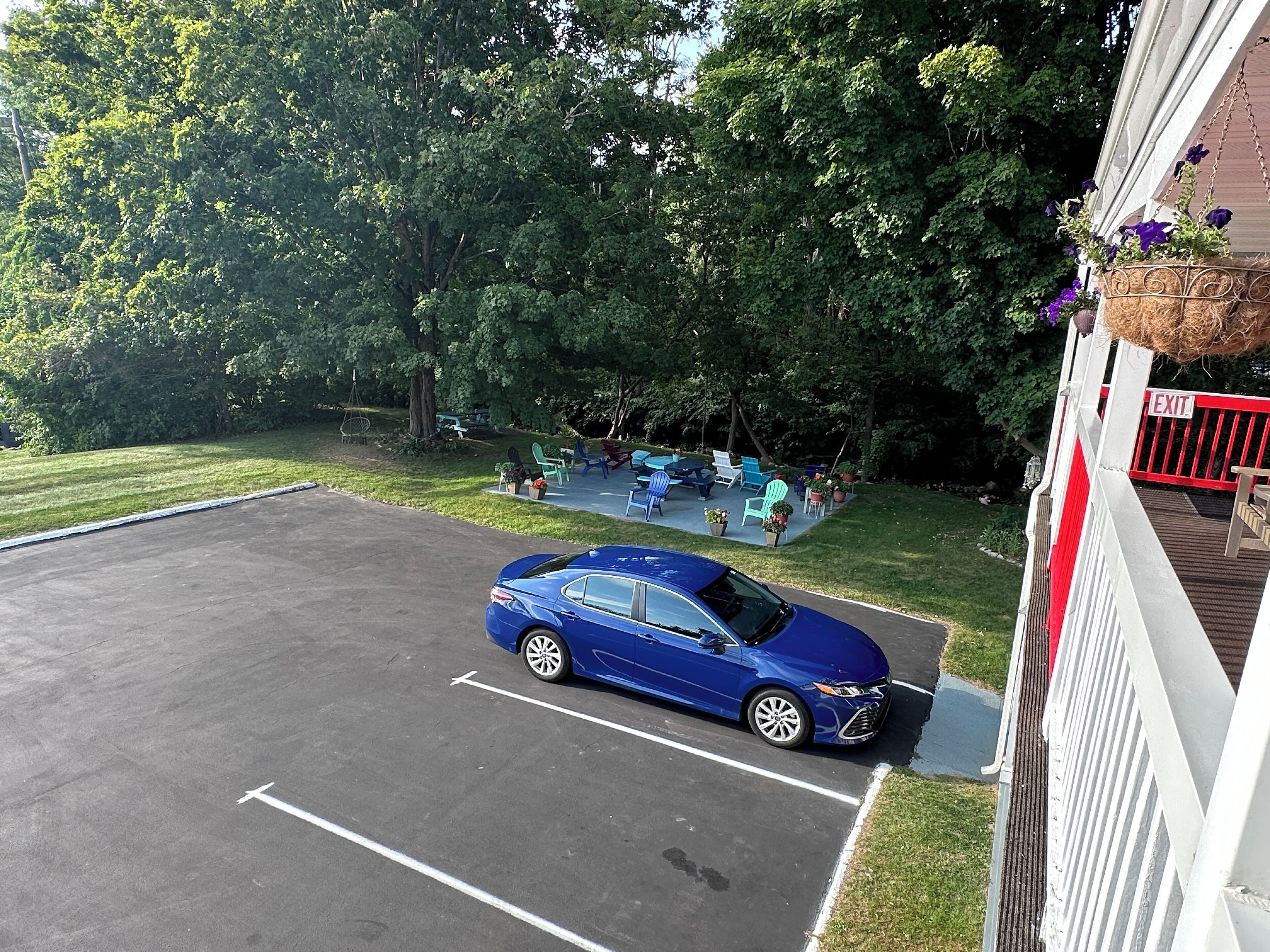 A parking lot with a blue car, outdoor seating area with chairs and tables, and a building with an 'EXIT' sign.