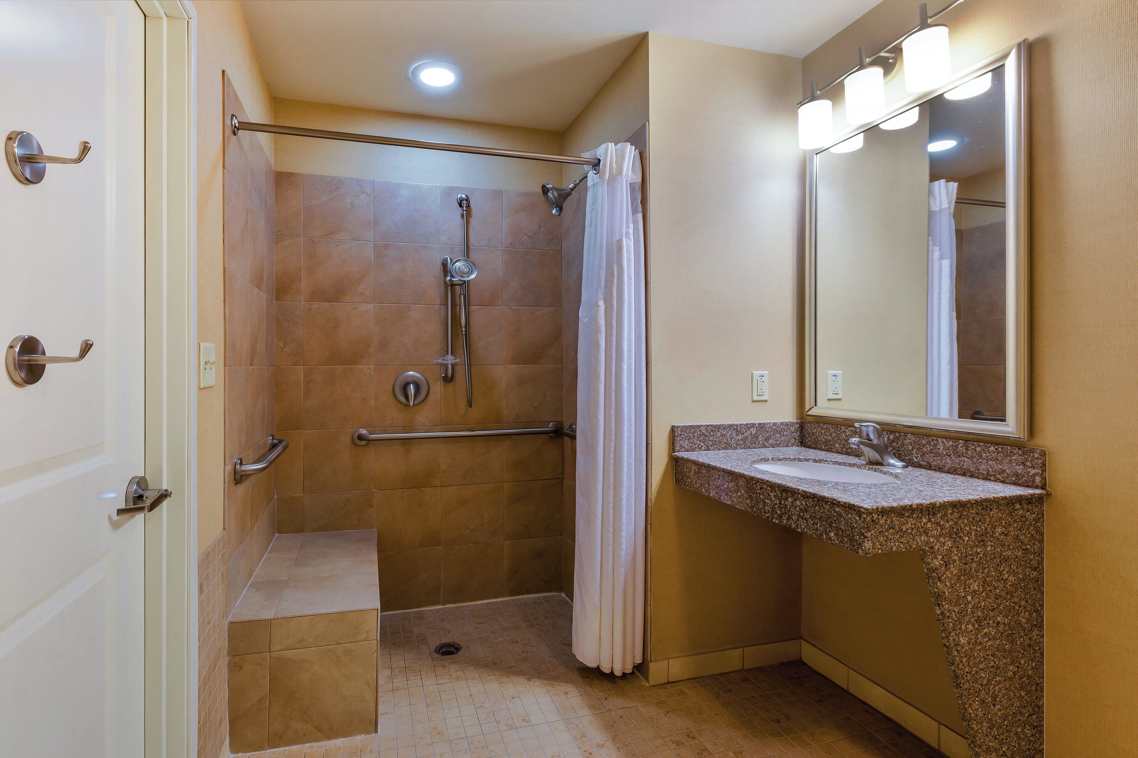 A bathroom with a shower, a sink, and a mirror.