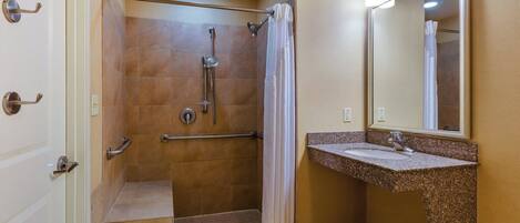 A bathroom with a shower, a sink, and a mirror.