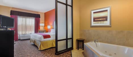 Ein Hotelzimmer mit Bett, Schreibtisch mit Fernseher, Badezimmer mit Badewanne und einem Bild an der Wand.