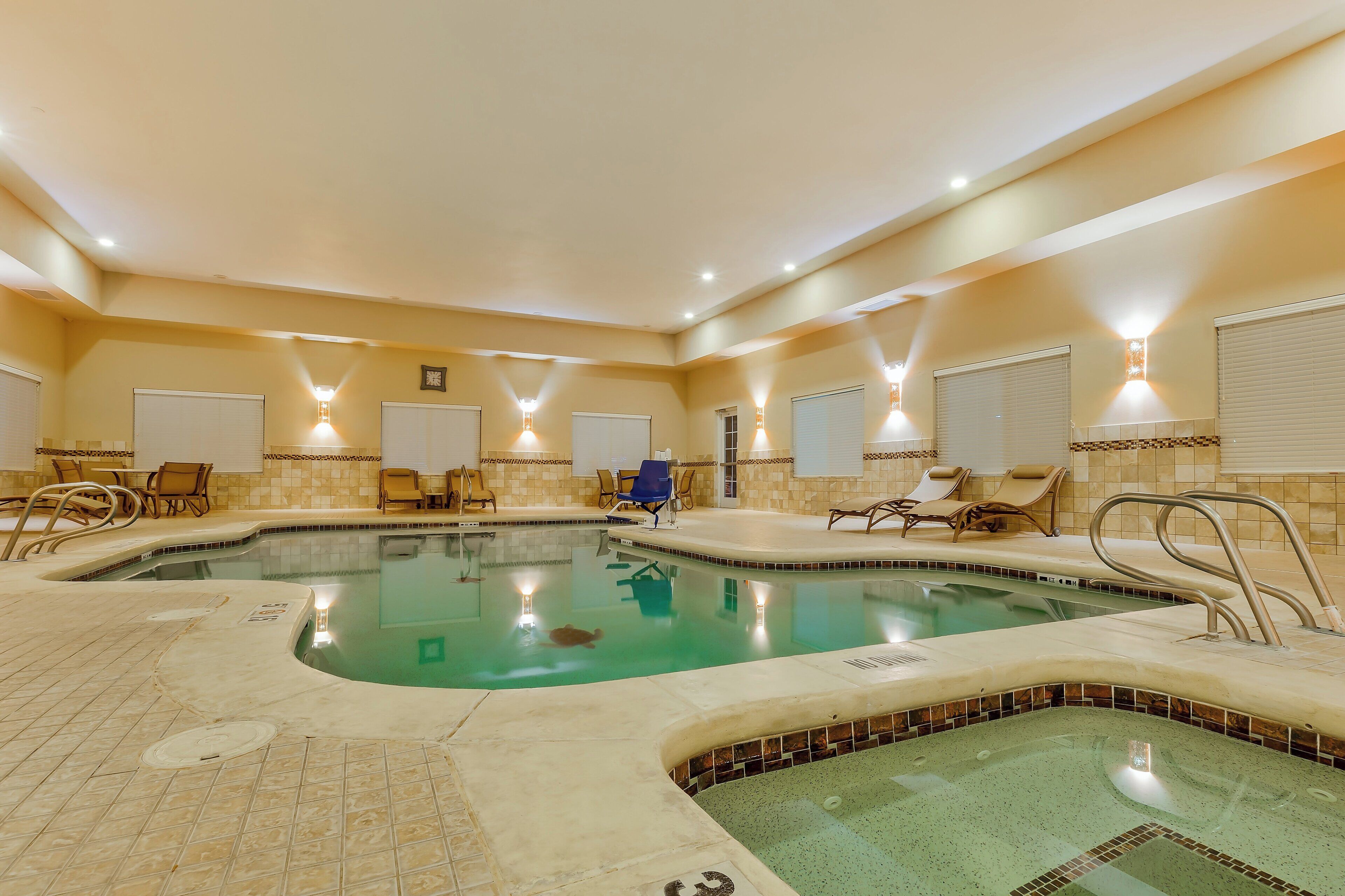 Una piscina interior con varias pistas, sillones de descanso y zona de jacuzzi.