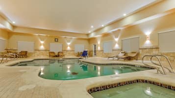 An indoor swimming pool with multiple lanes, lounge chairs, and a jacuzzi area.