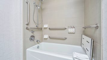 A modern bathroom with a bathtub, grab bars, a handheld showerhead, and a towel rack.