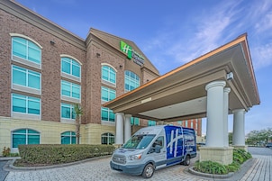 Edificio Holiday Inn Express con fachada de ladrillo, ventanas amplias y zona de acceso cubierta.