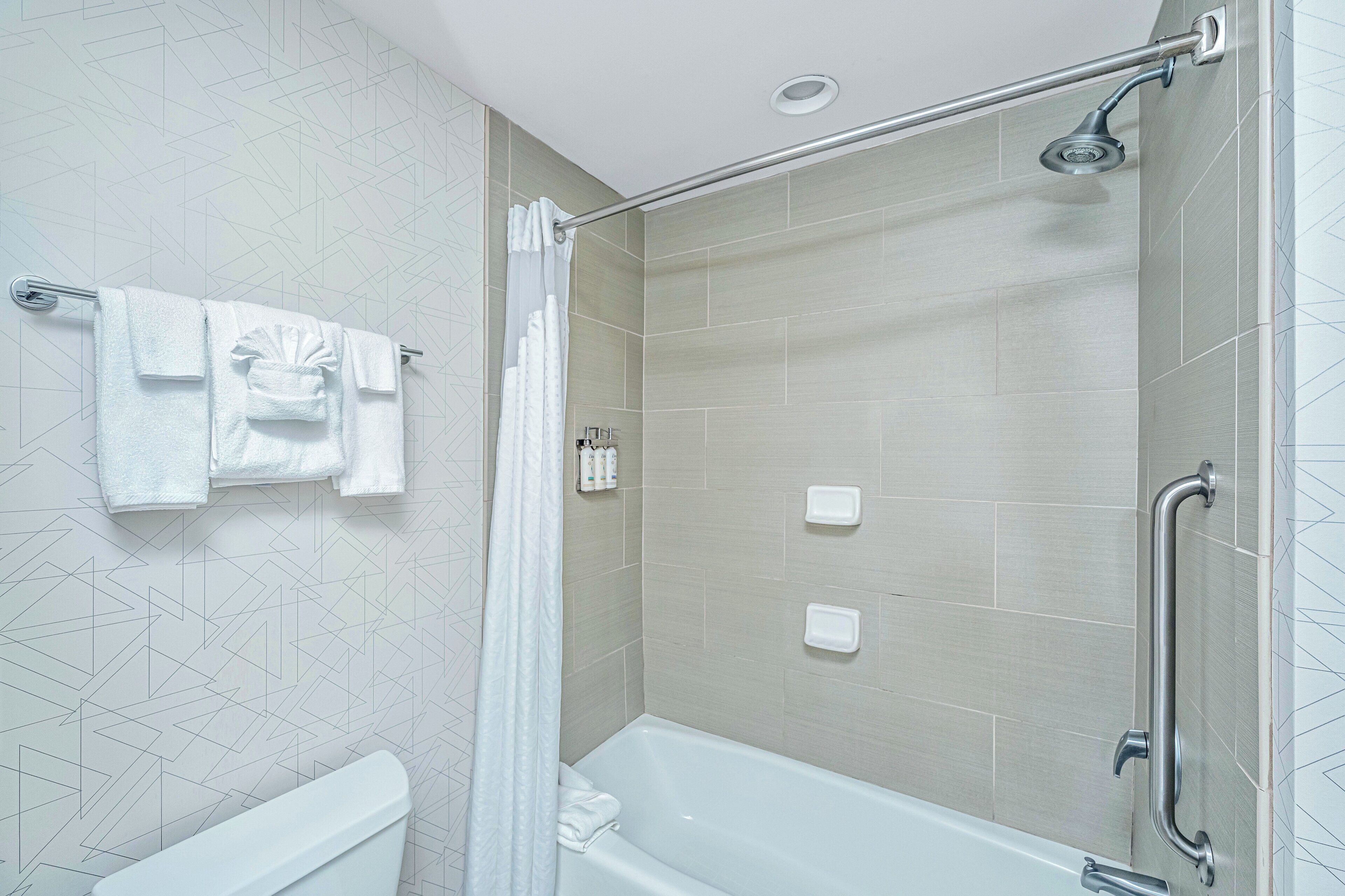Een moderne badkamer met een douche, een bad en een toilet.