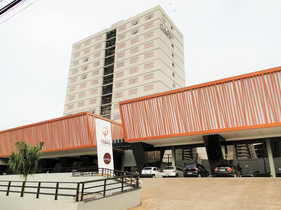 A hotel with a prominent building in the background, a covered parking area, and a sign for the Gran Odara Hotel.