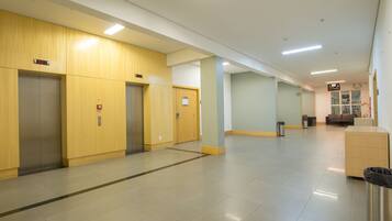 A clean, modern hallway with elevators and a trash bin.
