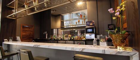 A bar area with a marble countertop, bar stools, and a variety of bottles and glasses.