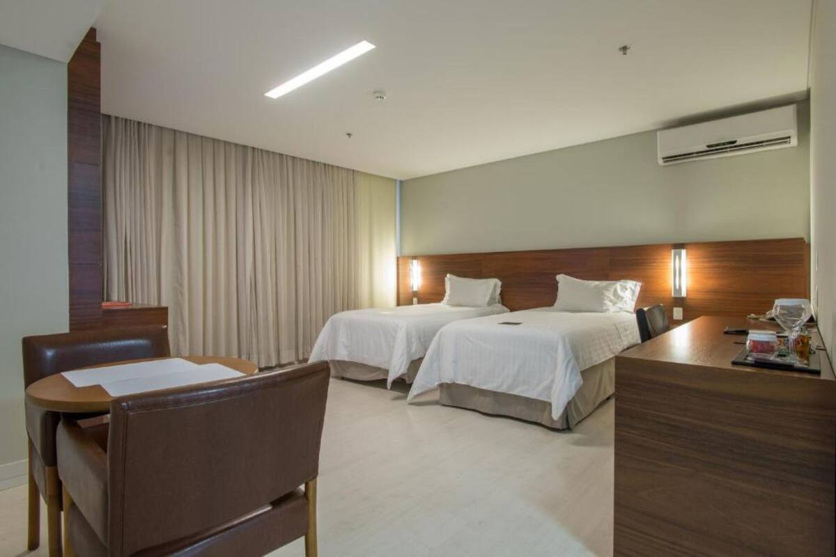 Una habitación de hotel con dos camas, un escritorio, una silla y un equipo de aire acondicionado.