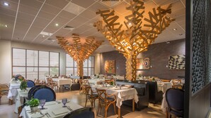 A restaurant with multiple tables, chairs, and a decorative ceiling structure. - Hotel Gran Odara (Cuiabá)