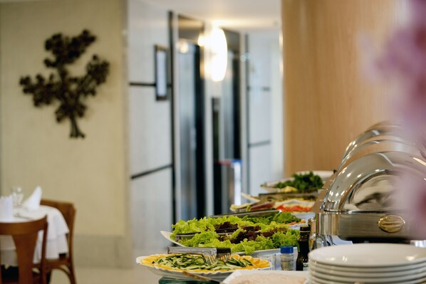A buffet table with various food items and a silver dome cover. - Quality Hotel Vitoria (Vitoria)