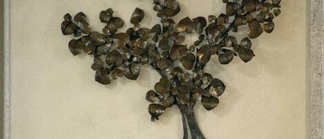 A dining table with a metal tree decoration on the wall behind it.