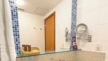 Un baño con lavamanos de vidrio, un espejo y un perchero para toallas.