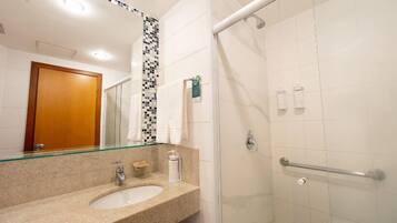 Un baño con lavamanos, espejo, ducha y barras de apoyo.