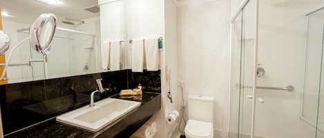 A modern bathroom with a glass-enclosed shower, a white sink, and a large mirror.