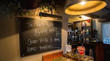 A chalkboard menu at a pub with items like 'Secret Recipe in Home Roast Tomatoes' and '£6'.