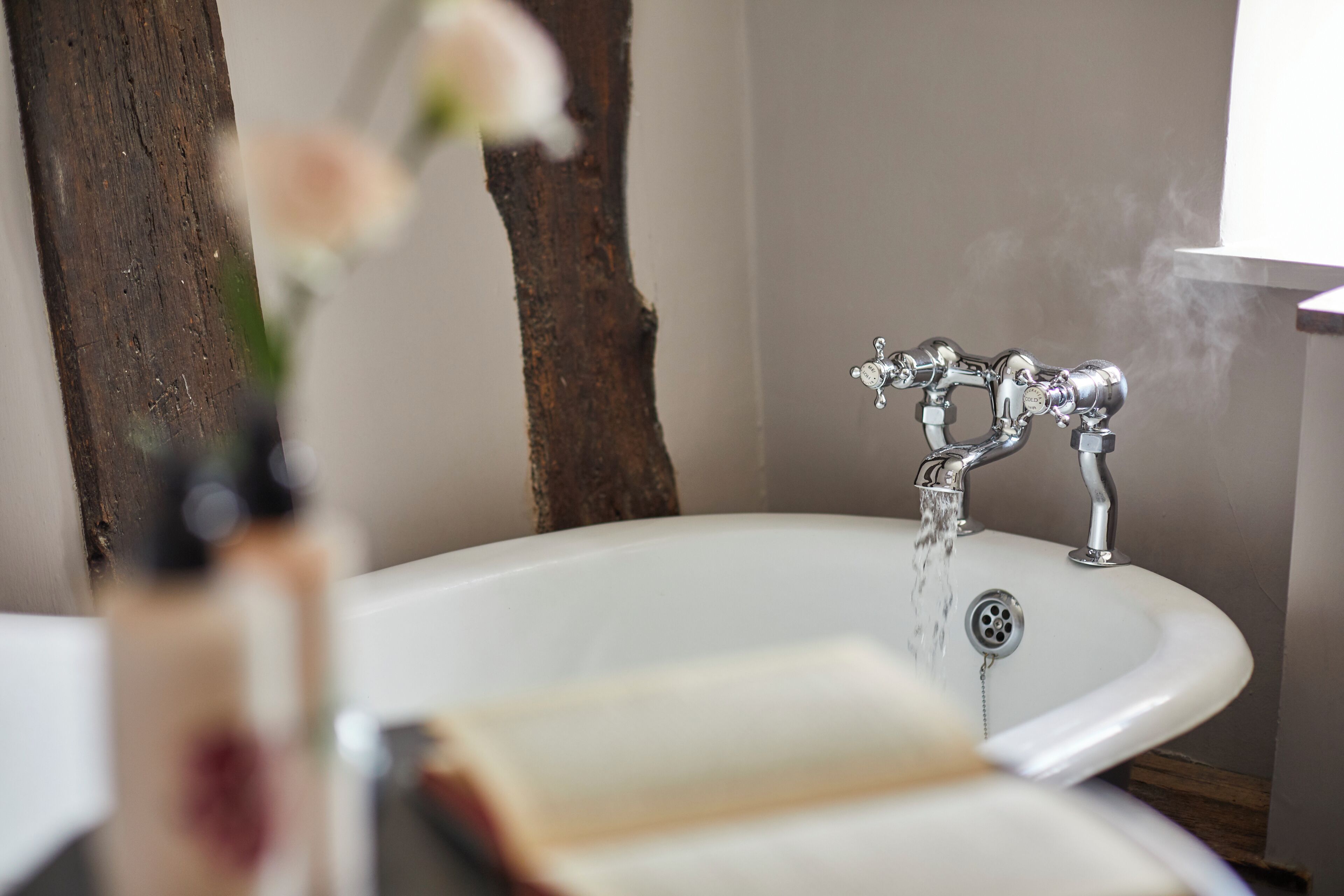 Une salle de bain avec une baignoire, un miroir et un mur en bois.