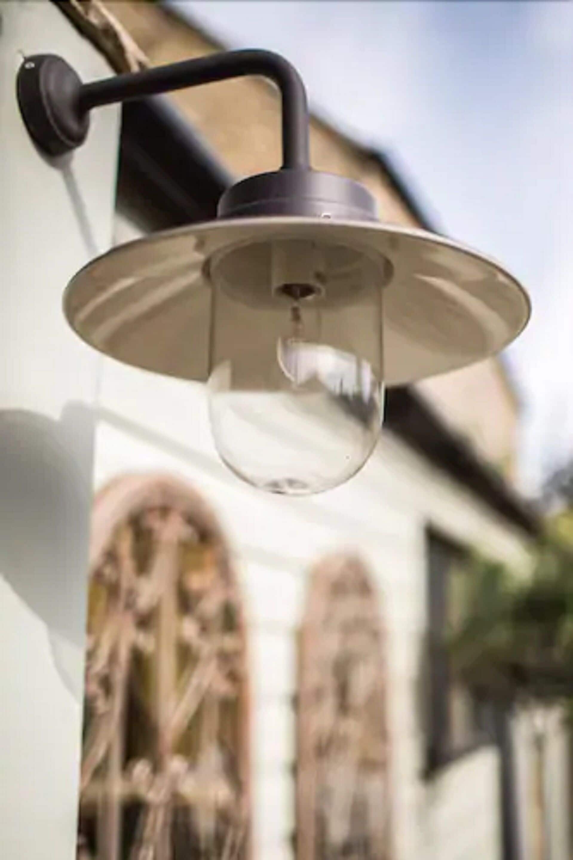 A wall-mounted outdoor light fixture with a clear glass cover and a black arm.