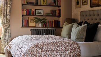 A bedroom with a large bed, a bookshelf, a radiator, and a window with curtains.