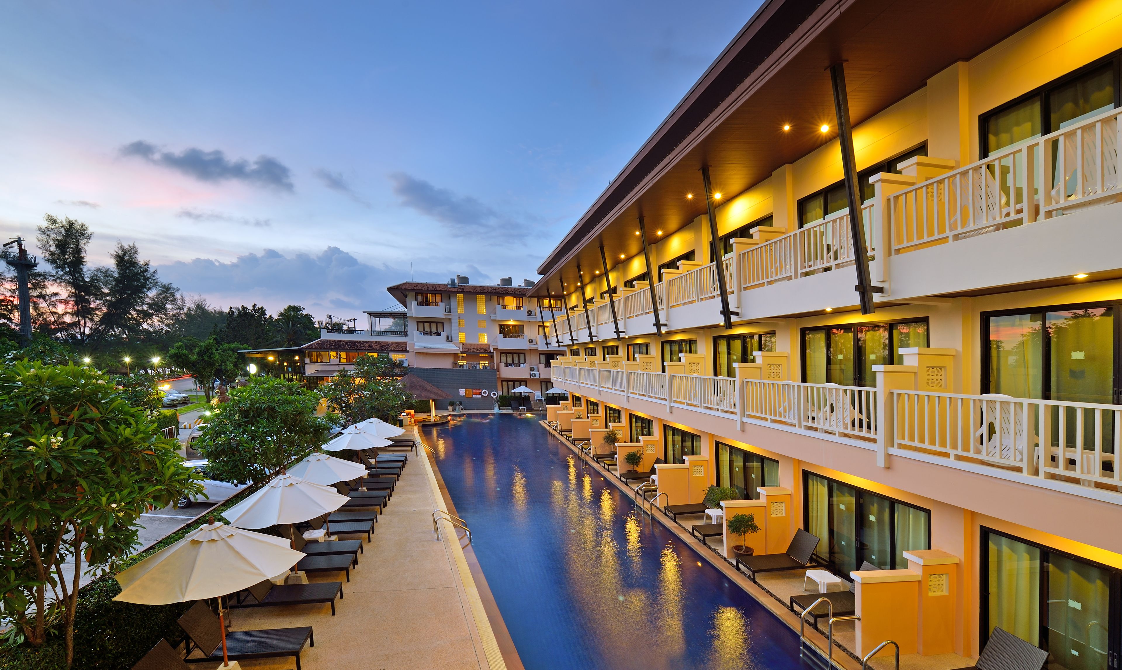Un hotel con piscina, mobiliario exterior y varios balcones.