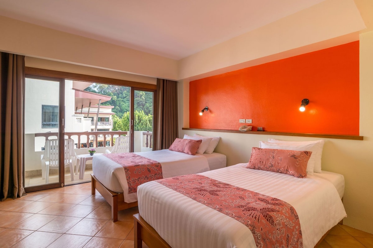 A hotel room with two beds, a balcony, and a red accent wall.