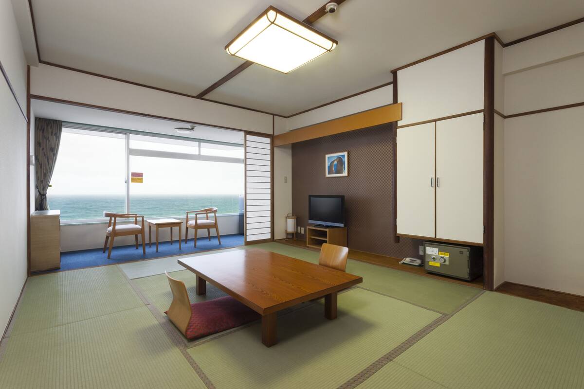 Une chambre d’hôtel avec une grande fenêtre, une table en bois, un téléviseur et un coffre-fort.