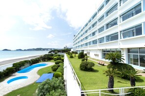 Un hôtel doté d’une piscine, d’une pelouse bien entretenue et offrant une vue sur la plage.