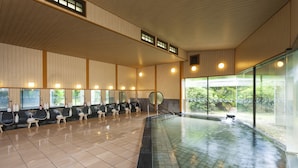Un espace piscine intérieur propre et moderne, avec un sol carrelé, plusieurs bancs et un mur de verre donnant sur la verdure à l’extérieur.