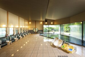 Ein moderner Poolbereich im Innenbereich mit mehreren Sitzbereichen und freiem Blick ins Freie.