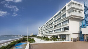 Un hôtel moderne à plusieurs étages, doté d’une piscine et offrant une vue sur la plage et l’océan.