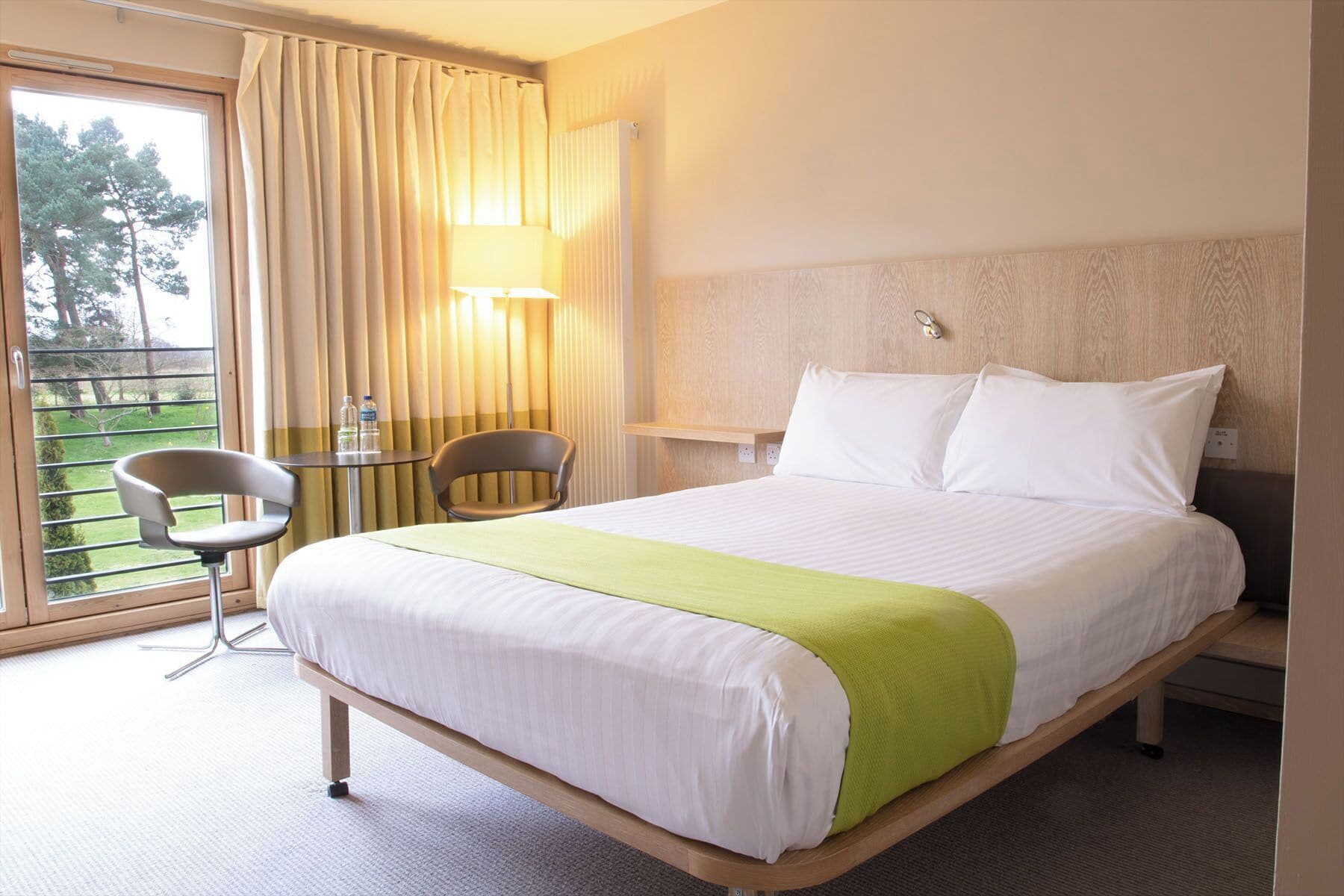 Una habitación de hotel con cama, una silla, una mesa y vistas al exterior.