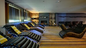 A spa area with multiple massage chairs, a fireplace, and a wall of bookshelves. - Lifehouse Spa & Hotel (Clacton-on-Sea)