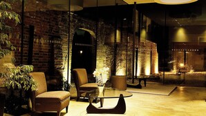A modern interior with a brick wall, a glass partition, and a seating area with a coffee table. - Lifehouse Spa & Hotel (Clacton-on-Sea)