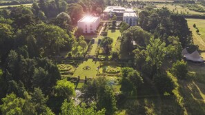 An aerial view of a property with a central building surrounded by manicured gardens, a small pond, and a tent-like structure. - Lifehouse Spa & Hotel (Clacton-on-Sea)