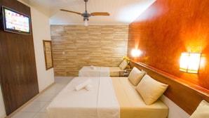 A hotel room with two beds, a ceiling fan, a TV, and a wooden accent wall. - Shangrilá - Rede Soberano (Porto Seguro)