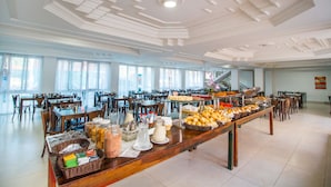 A buffet setup with various food items and a large dining area with tables and chairs. - Shangrilá - Rede Soberano (Porto Seguro)