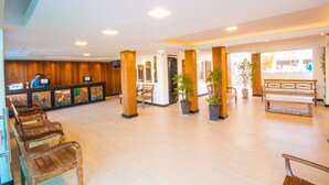 A spacious lobby with wooden benches, potted plants, and a reception desk. - Shangrilá - Rede Soberano (Porto Seguro)