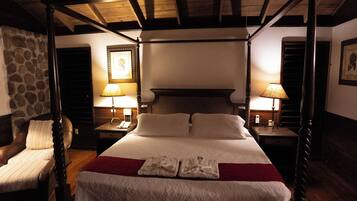 A four-poster bed with white linens and a red throw blanket, flanked by two nightstands with lamps.