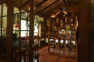 A room with wooden floors, a ceiling fan, and shelves filled with pottery.