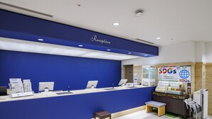 A reception area with a blue counter, a small table, and a refrigerator displaying beverages. - Airline Hotel (Miyazaki)